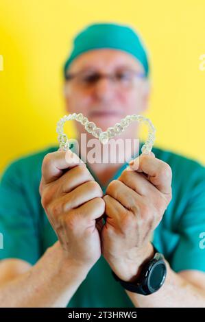 Doctor holding two heart-shaped clear dental aligners Stock Photo