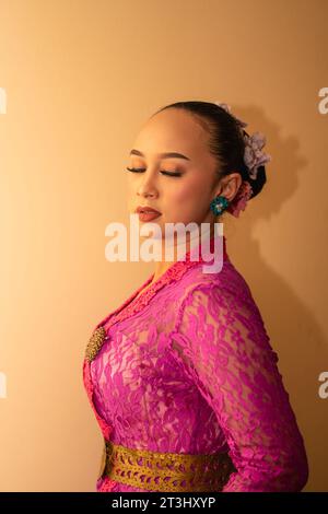 Balinese bride wearing the pink wedding dress before the ceremony has started inside the temple Stock Photo