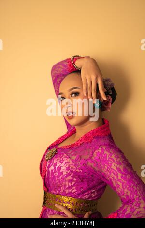 Balinese mother wearing a pink dress called kebaya and make-up before praying in the temple Stock Photo