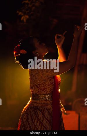 Balinese women wearing cultural clothes while posing in front of the lighting with dancing movements on their body Stock Photo