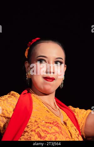 Indonesian woman in makeup with red lips wearing a golden necklace and golden earrings before dancing on the stage Stock Photo