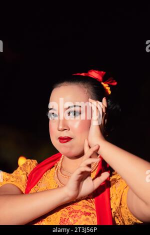 Indonesian woman in makeup with red lips wearing a golden necklace and golden earrings before dancing on the stage Stock Photo