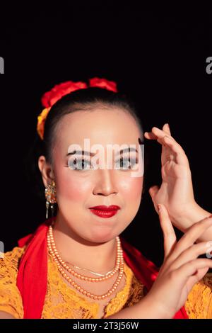 Indonesian woman in makeup with red lips wearing a golden necklace and golden earrings before dancing on the stage Stock Photo