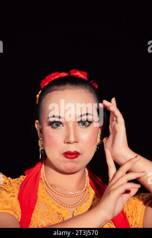 Indonesian woman in makeup with red lips wearing a golden necklace and golden earrings before dancing on the stage Stock Photo
