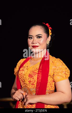 Cute Indonesian woman with red lips and a red scarf wearing a traditional Sundanese dress called kebaya inside the dance festival Stock Photo