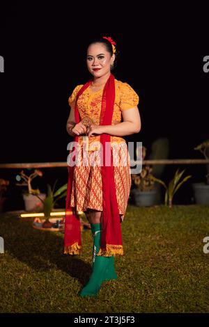 Cute Indonesian woman with red lips and a red scarf wearing a traditional Sundanese dress called kebaya inside the dance festival Stock Photo