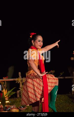 Asian woman performing a traditional dance called jaipong in Indonesia with a yellow dress and red scarf at the dance festival Stock Photo