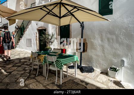 An empty restaurant table covered in green gingham,  ready for customers in Ostuni, Italy. Stock Photo