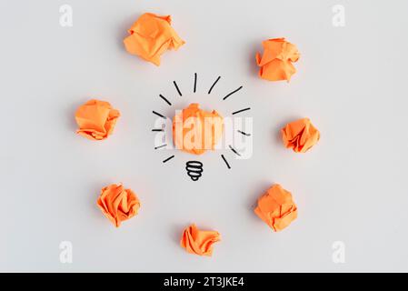 Light bulb with crumpled colorful paper white surface Stock Photo