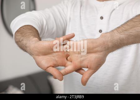 Man cracking his knuckles on blurred background, closeup. Bad habit Stock Photo