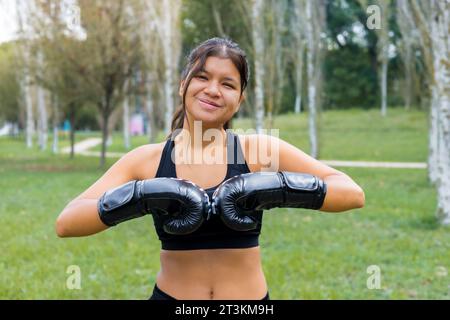 Young latin boxer woman putting on boxing gloves in an outdoor sparring training Stock Photo