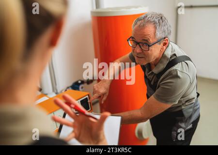 Team of heating engineers checks a old gas heating system at a boiler room in a house. Gas heater replacement obligation concept image Stock Photo