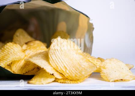 Crispy potato chips in a bag on a blue background Stock Photo