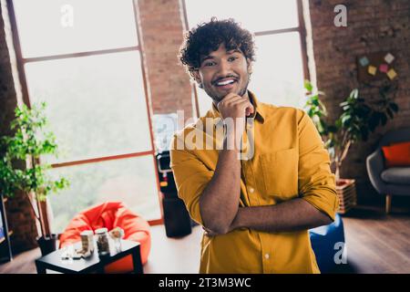 Photo portrait of young male wear yellow shirt touch chin thoughtful create small business plan interior loft industrial style Stock Photo