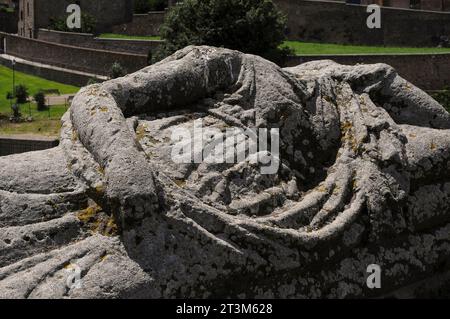 Lichen encrusted headless effigy of Ancient Etruscan in Tuscania, Lazio, Italy.  Carved on a sarcophagus lid, now displayed on the low western wall of the Piazza Franco Basile.  Tuscania was formerly the Ancient Etruscan city of Tuscana.  It lies about 80 km (50 miles) north-west of Rome. Stock Photo