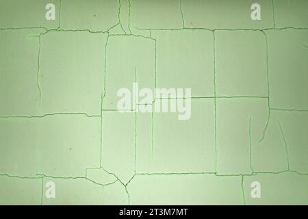 Cracks in paint. Green paint is cracked. Texture of wall. Chaotic lines on surface. Stock Photo