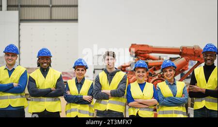 Multiracial workers inside robotic factory - Men and women at work and diversity concept - Focus on center guy face Stock Photo
