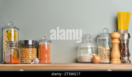 Kitchen shelf for storing food in glass jars on a pastel green wall background. Copy space Stock Photo