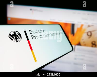 Cellphone with logo of German agency Deutsches Patent- und Markenamt (DPMA) in front of website. Focus on left of phone display. Stock Photo