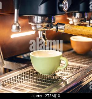 Freshly brewed coffee is poured from the coffee machine into cup Stock Photo
