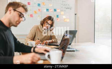 businessmen and businesswomen brainstorm and work together on a project in a creative office. The team, including a scrum master, focuses on software Stock Photo