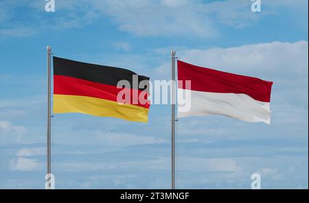 Indonesia and Germany flags waving together on blue cloudy sky, two country relationship concept Stock Photo