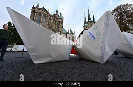 26 October 2023, Thuringia, Erfurt: Nine of a total of 100 five-meter-long paper boats, which will be set up in front of the Bundestag for World Refugee Day on June 20, 2024, will be presented on Erfurt's Domplatz. The project of the AWO Volunteer Academy Saxony-Anhalt reminds nationwide with 100 paper boats of about 100 million people who are on the run worldwide. Photo: Martin Schutt/dpa Stock Photo