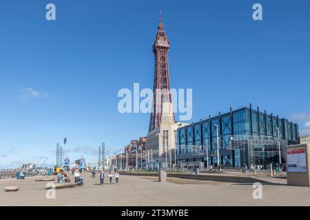 Blackpool Tower viewed from The Promenade with tourists walking along it. Stock Photo