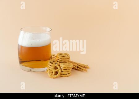 Glass of frothy, refreshing beer with pretzel on yellow background. Copy space. Stock Photo