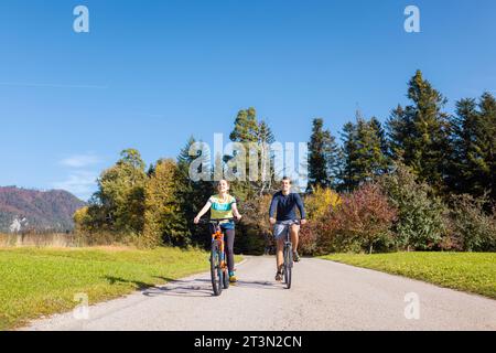 Young smiling, relaxed couple enjoying a bike ride in a beautiful countryside. Active autumn vacation concept. Stock Photo