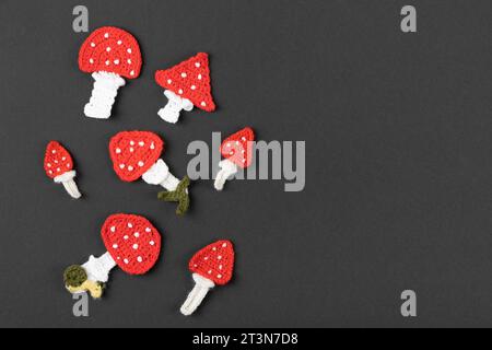 Knitted toys mushrooms fly agaric on a black background. Baby stuff and accessories. Halloween greeting card mockup with copy space. Happy Halloween h Stock Photo