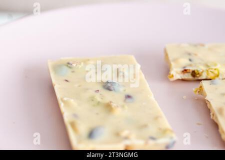 white chocolate with pistachios on pink background in close-up Stock Photo