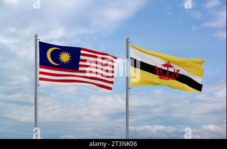 Brunei and Malaysia flags waving together on blue cloudy sky, two country relationship concept Stock Photo