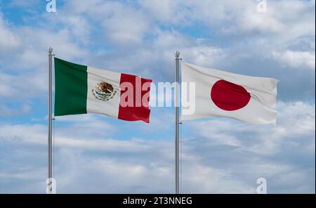 Japan and Mexico flags waving together on blue cloudy sky, two country relationship concept Stock Photo