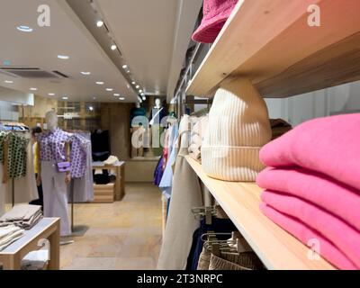 A close-up shot highlights a wool winter cap in a clothing store, with mannequins dressed in stylish clothes as a backdrop, creating a fashionable scene. Stock Photo