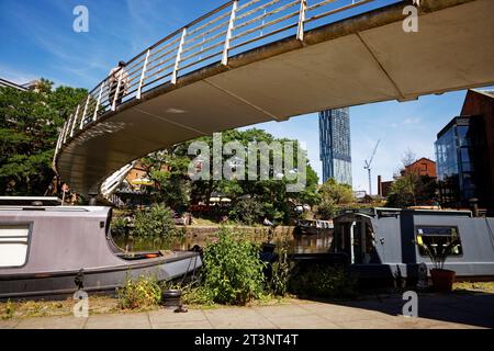 Barges moored below a footbridge over Castlefield Basin on the Bridgewater Canal in Manchester City Centre. Stock Photo