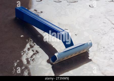 Studio shot of a plastic disposable razor on a wet slate background - John Gollop Stock Photo