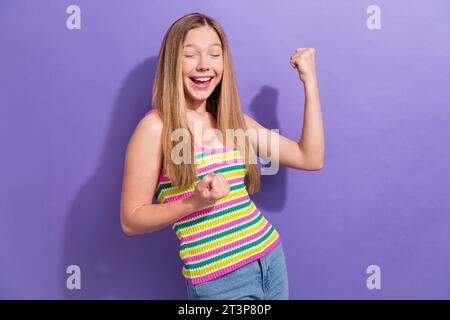 Photo of overjoyed funny schoolgirl with straight hairdo dressed striped top scream yeah win lottery isolated on violet background Stock Photo