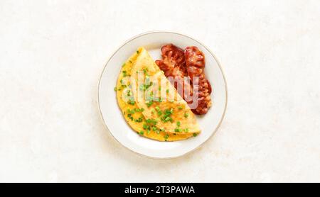 Omelette with cheese and green onion on plate over light background with free space. Tasty healthy dish for breakfast. Top view, flat lay. Stock Photo