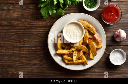 Potato wedges with dipping sauce over wooden background with free space. Top view, flat lay Stock Photo