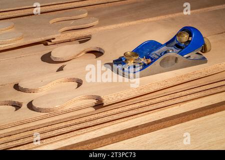 block plane and narrow panels of okoume plywood with puzzle joints from a stitch-and-glue boat building kit Stock Photo