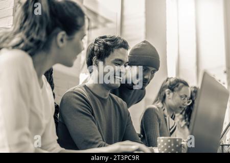 Young co-workers multiethnic team planning a new startup - Happy computer programmers working on a new project in creative coworking office - Black an Stock Photo