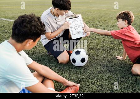 School children with coach teacher during sport training session at soccer field - Fitness and education concept Stock Photo