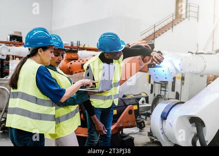 Multiracial engineers working with robot arm at robotic warehouse facility - People and Industrial AI business Stock Photo