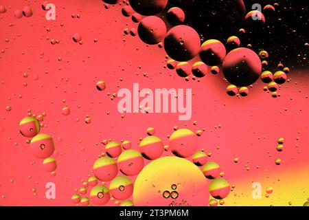 Macro photography with circles oil droplets water surface. Abstract with yellow, black and red background with oil bubbles Stock Photo