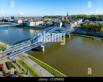 Krakow, Poland. Pilsudski blue tied arc bridge over Vistula River with tramway,  blue tram, sidewalk and bicycle lane. Boulevards on riverbanks. Podgo Stock Photo