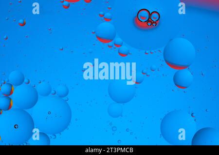 Macro photo with circles oil droplets water surface. Abstract blue and red background with oil bubbles Stock Photo