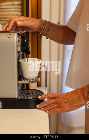 Detail of coffee pot pouring coffee in the cup, vertical photo Stock Photo