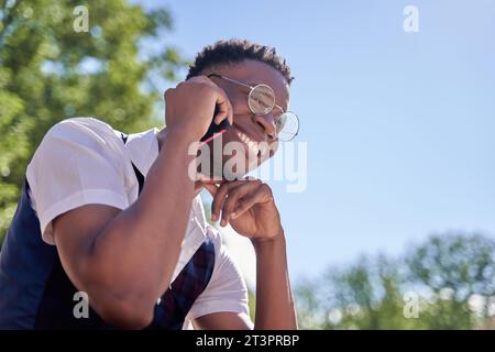 Young african american man laughs while talking on the phone on the street. Stock Photo
