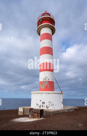Low angle shot of the Punta Sardina lighthouse, in Gran Canaria island, Spain. Painted in horizontal red and white stripes with cloudy sky and sea in Stock Photo